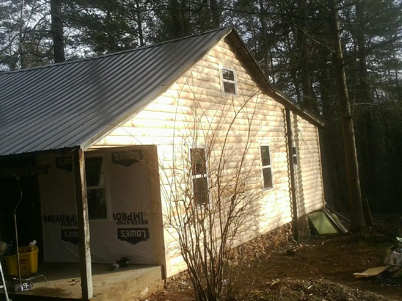 Log siding gable end under a dark metal roof edge in Brownsville